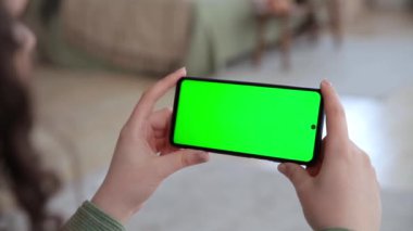 Anahtar yeşil ekranlı, yatay akıllı telefon kullanan kadın elleri görüntüsünü kapat. Chroma tuşu, yayın hizmetleri uygulamaları için bir model oluşturur. İnternette video izliyorum. Seçici odak.