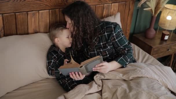 Młoda Kobieta Czyta Bajki Synowi Przed Pójściem Łóżka Pocałowaniem Dziecko — Wideo stockowe