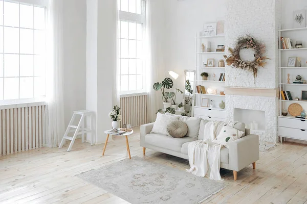 stock image Modern stylish white living room with large windows and scandinavian style sofa against the backdrop of a fireplace and shelving and potted plants. Nobody.