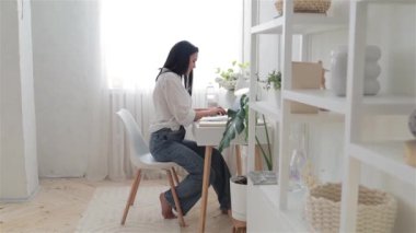 Genç serbest çalışan kadın bir projeyi yeni tamamladı ve bundan çok mutlu. Beyaz ofis masasında dizüstü bilgisayarda çalışan bir kadın. Serbest çalışma kavramı, evde uzak çalışma, çevrimiçi öğrenme.