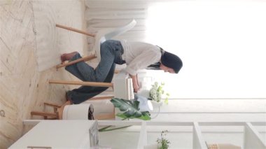 Dikey video. Genç kadın serbest yazar ya da öğrenci beyaz masa başında dizüstü bilgisayar kullanıyor ve çevrimiçi çalışıyor, webinar izliyor, bilgisayar ekranı öğrenme web derslerine bakıyor ya da evden uzakta çalışıyor..