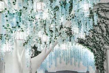 Elegant white tree adorned with blue flowers and lanterns, creating enchanting ambiance. Soft decorative lanterns adds the serene and magical environment. Green leaves and intricate decor add charm. clipart