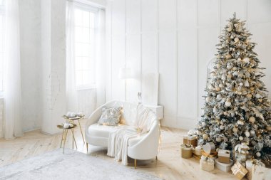 Noel için beyaz bir kanepe, şenlik ağacı ve hediyelerle süslenmiş zarif bir yaşam alanı. Altın ve beyaz tonlu minimalist tasarım sıcak ve davetkar bir tatil ortamı yaratır..