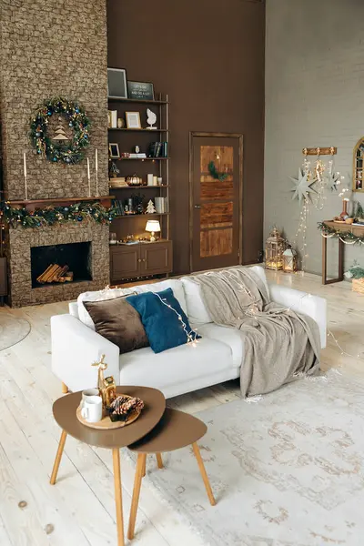 Yastıklı kanepe ve Noel 'de şömineli, kitaplı ve dekorlu rahat bir oturma odasında ekose kumaş. Şöminenin üzerinde Noel çelengi var. Noel dekorlu oda.