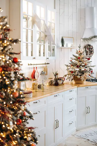 Noel için ahşap tezgahlı beyaz mutfak. Süslü küçük bir Noel ağacı, kabinede bir yıldız ve şenlikli aksesuarlar rahat bir tatil ortamı yaratır..