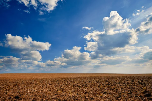 stock image Clouds over the plowed agricultural field on a warm sunny day. Landscape panorama.