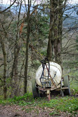 Su için küçük klasik tarım plastik tankı ya da ormanlık alana park edilmiş yapay gübreler. Tarlada çalışırken, bir traktör tarafından sürüklenir ve hortum ve borularla ona bağlanır. Paslı tekerlekler yaşlarına tanıklık ediyor.