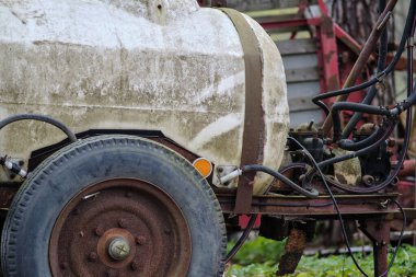 Su için küçük klasik tarım plastik tankı ya da ormanlık alana park edilmiş yapay gübreler. Tarlada çalışırken, bir traktör tarafından sürüklenir ve hortum ve borularla ona bağlanır. Paslı tekerlekler yaşlarına tanıklık ediyor.