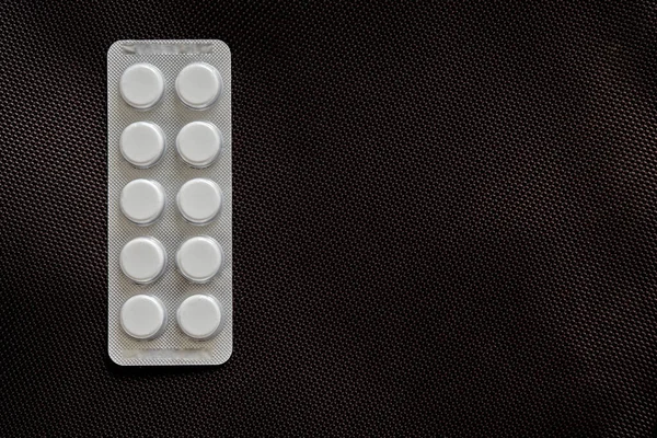 Verpackung Mit Runden Pharmazeutischen Medikamententabletten Auf Einem Dunklen Groben Textiltuch — Stockfoto