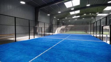 Spor tesisi bölgesinde bulunan bir depo binasının içindeki mavi padel tenis kortlarının görüntüsü. Gündüz aydınlatma armatürleri aydınlatılmış