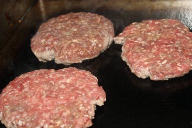 double cheeseburger with fries in the shape of a smiley face. Hamburger topped with bacon, onion and peppers. Melted cheddar and sesame seed bread.