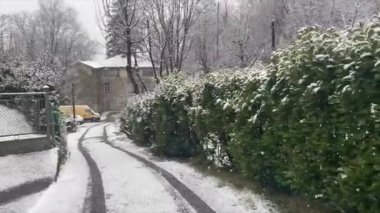 Panoramic view of an ancient village in northern Italy under a snowstorm with large and thick flakes. Trees and white houses covered in several inches of snow. walk behind snow plow blower. Dust of snow. Living crystals.