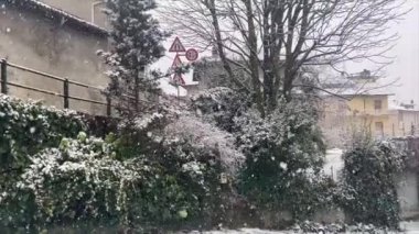 Panoramic view of an ancient village in northern Italy under a snowstorm with large and thick flakes. Trees and white houses covered in several inches of snow. walk behind snow plow blower. Dust of snow. Living crystals.