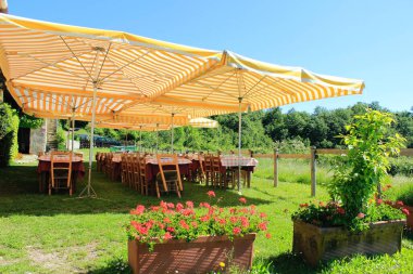 Masaları, sandalyeleri ve geniş renkli şemsiyeleri olan bahçe Paskalya 2023 parti yemeği için hazır. İtalya 'da dini bayramların kutlanması. Şehir dışında Paskalya yemeği.