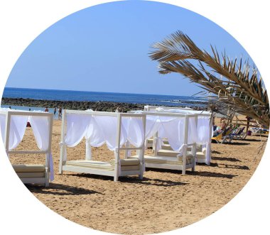 Zarif, uyumlu, manzaralı ve lekesiz beyaz balkonların panoramik manzarası. Güneşli kumsalın ılık rüzgarında perdeleri kanat çırpan güneşli yataklar. Zengin ve aristokratlar için plaj tatili.