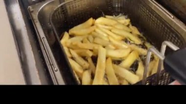 Patatesler kızgın yağda kızarıyor. Profesyonel kızartma makinesi. Restoran mutfağı. Kızartma sepeti.