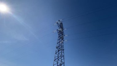 Yüksek voltajlı elektrik direğinin panoramik görüntüsü. Yüksek voltajlı elektrik kabloları için demir desteği. Kavşağın ortasında kutup var..