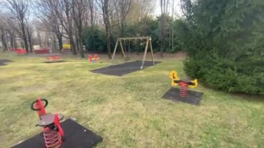 Boş çocuk parkında salıncaklarla, hareketsiz ve yalnız eğlencelerle yürü. Çocuklar için belediye yeşili.