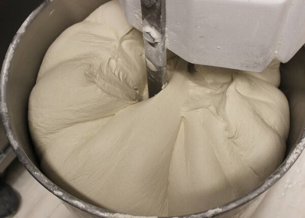 Mechanical pizza mixer at work. Raw dough in rotation. High hydration. Pizza base in production with mechanical machine.