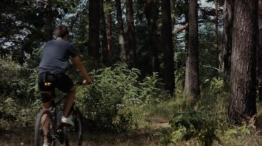 Unrecognizable man riding bicycle in the forest