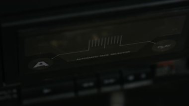Elle ses kaseti yerleştirir ve klasik stereo teyp kayıt cihazındaki oynat düğmesine basar. Yakın plan..
