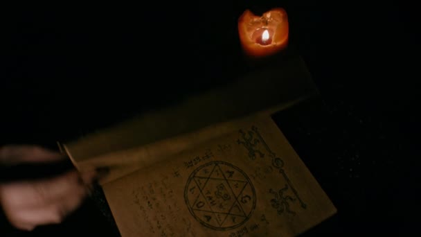 Рука Відкриває Книгу Чорної Магії Палаючою Свічкою Зблизька Концепція Чаклунства — стокове відео