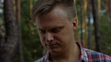Young man checking prepared wooden stick for camping. Rack focus.