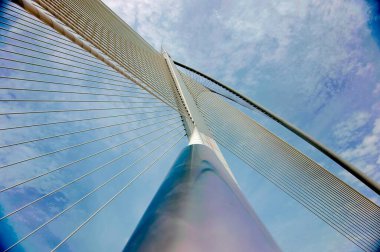 Üzerinde kablo olan bir köprü. Gökyüzü bulutlu ve köprü gökyüzünün ortasında.