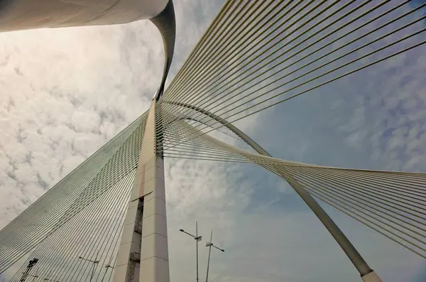 A bridge with a wire running across it. The sky is cloudy and the bridge is in the middle of the sky