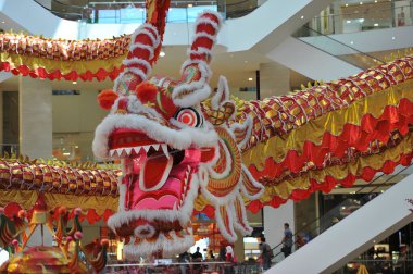 Büyük bir ejderha süslemesi olan alışveriş merkezindeki adamlar. Kırmızı fenerler ve kiraz ağaçları şenlikli atmosfere eklenir..