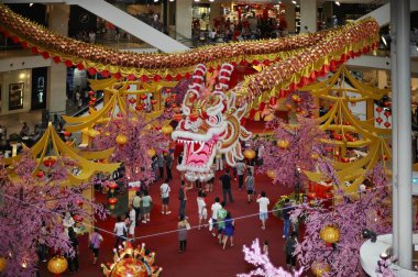 Büyük bir ejderha süslemesi olan alışveriş merkezindeki adamlar. Kırmızı fenerler ve kiraz ağaçları şenlikli atmosfere eklenir..