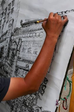 Çinli bir adam, tarihi bir sokak sahnesinde yerel halk mimarisinin ve ticaretinin özünü yakalayan hareketli bir şehir manzarası çiziyor..