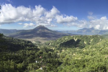 Endonezya, Bali 'de yemyeşil ve uzak dağlarla çevrili Batur Dağı' nın panoramik manzarası. Görüntü huzurlu ve görkemli bir doğal görüntü yakalıyor..