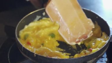 Bir tava çırpılmış yumurta ve ahşap bir spatula.