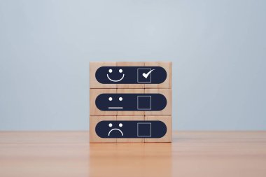 Parlak tarafta gülen yüz, karanlık tarafta üzgün yüz, tahta blok küpte olumlu zihniyet seçimi, müşteri anketi ve tatmin geri bildirimi konsepti..