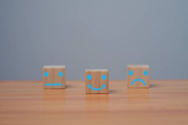 Parlak tarafta gülen yüz, karanlık tarafta üzgün yüz, tahta blok küpte olumlu zihniyet seçimi, müşteri anketi ve tatmin geri bildirimi konsepti..