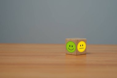Parlak tarafta gülen yüz, karanlık tarafta üzgün yüz, tahta blok küpte olumlu zihniyet seçimi, müşteri anketi ve tatmin geri bildirimi konsepti..