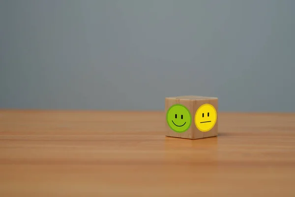 Smile face in bright side and sad face in dark side on wooden block cube for positive mindset selection, Customer experience survey and satisfaction feedback concept.