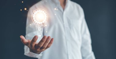 Fikir yeniliği ve ilham kavramı. Elinde yanan ampul, fikir yeniliği ve ilham konsepti olan bir adamın eli. Işıldayan ampullerle yaratıcılık, başarı kavramı.