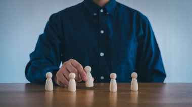  İnsan Kaynakları Yönetimi ya da Personel İşe Alma Konsepti. Kalabalıktan bir personel lideri seçmek. İş adamı bir çalışanı elinde tutuyor. Ahşap blok insanları.