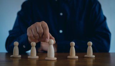  İnsan Kaynakları Yönetimi ya da Personel İşe Alma Konsepti. Kalabalıktan bir personel lideri seçmek. İş adamı bir çalışanı elinde tutuyor. Ahşap blok insanları.