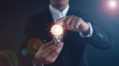  Online teknolojiden ilham alma fikri. Yenilik fikri. İçinde bir ampul ve dişli simgesi var. Ve o bir dizüstü bilgisayar kullanıyor.. 