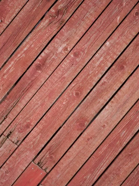 Old rustic board wall painted with red mulch paint on the diagonal. High quality photo