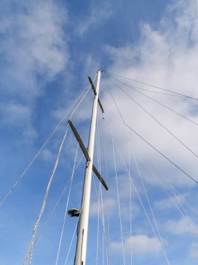 Bir yelkenli gemisinin direği beyaz bulutlu gökyüzünün arka planında