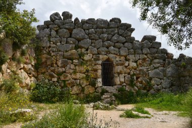 Tarihi taş duvar, Sally Limanı giriş kapısının demir ızgarası. Asırlık efsaneye göre The Walls of Mycenae Cyclops tarafından inşa edilmiş. Bugünlerde çiçekler sert antik kayalara tırmanıyor. Yunanistan, Mora 'lı.