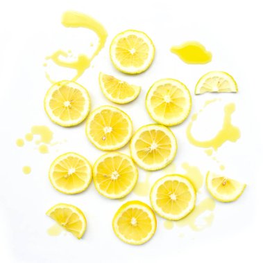 Limon dilimleri ve biraz zeytinyağı. Citrus, parlak sarı taze parçaların üst görüntüsü ve beyaz zemine dökülen yağ damlalarının soyut deseni. Yunan gıda malzemeleri. 