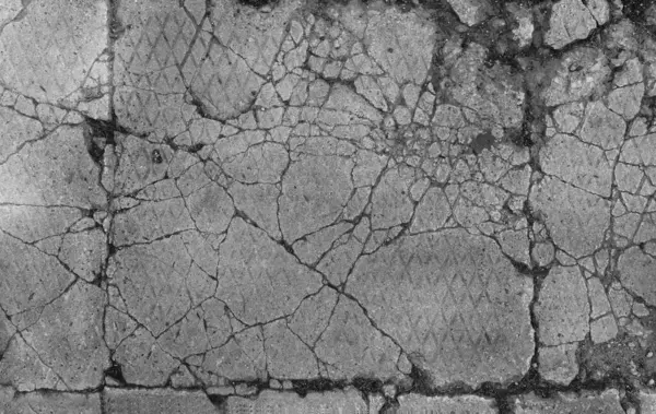 バックグラウンドテクスチャとして古い割れたコンクリート 損傷したセメントの表面の閉鎖は 光沢のあるダイヤモンドパターンで 太陽と影の輝く網の下にあります サイドウォーク 細かい破片を収集する深いスプリットが付いている舗装 — ストック写真