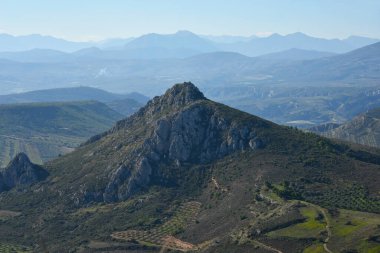 Kayalık tepenin tepesinde eski kalıntılar ve bahçeler var. Yüzlerce yıllık Penteskoufi Kalesi. Efsanevi Acrocorinth kalesinden manzara, arka planda dağlar. Geçmiş, şimdiki zaman, Peloponese, Yunanistan.