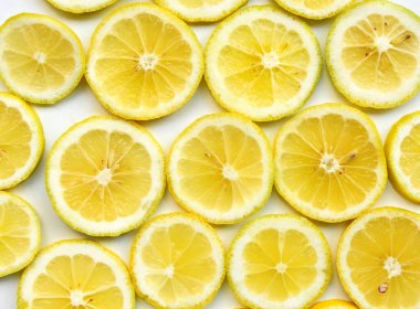 Limonlar beyaz arkaplanda yakın plan çekimde kesiliyor. Üst Manzara. Parlak daireler halinde küçük güneşler gibi görünen sulu parçalardan oluşan canlı ve soyut bir desen. Taze sağlıklı yiyecek, Yunan bahçesinden lezzetli meyve..