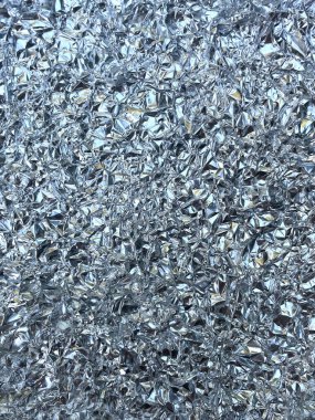 Gümüş metal buruşuk folyo kaplama, arka plan olarak buruşuk grunge dokusu. Kırışık, kırışık alüminyum folyoların parlak, yansıtıcı yüzeyi ve rastgele katlama desenleri..